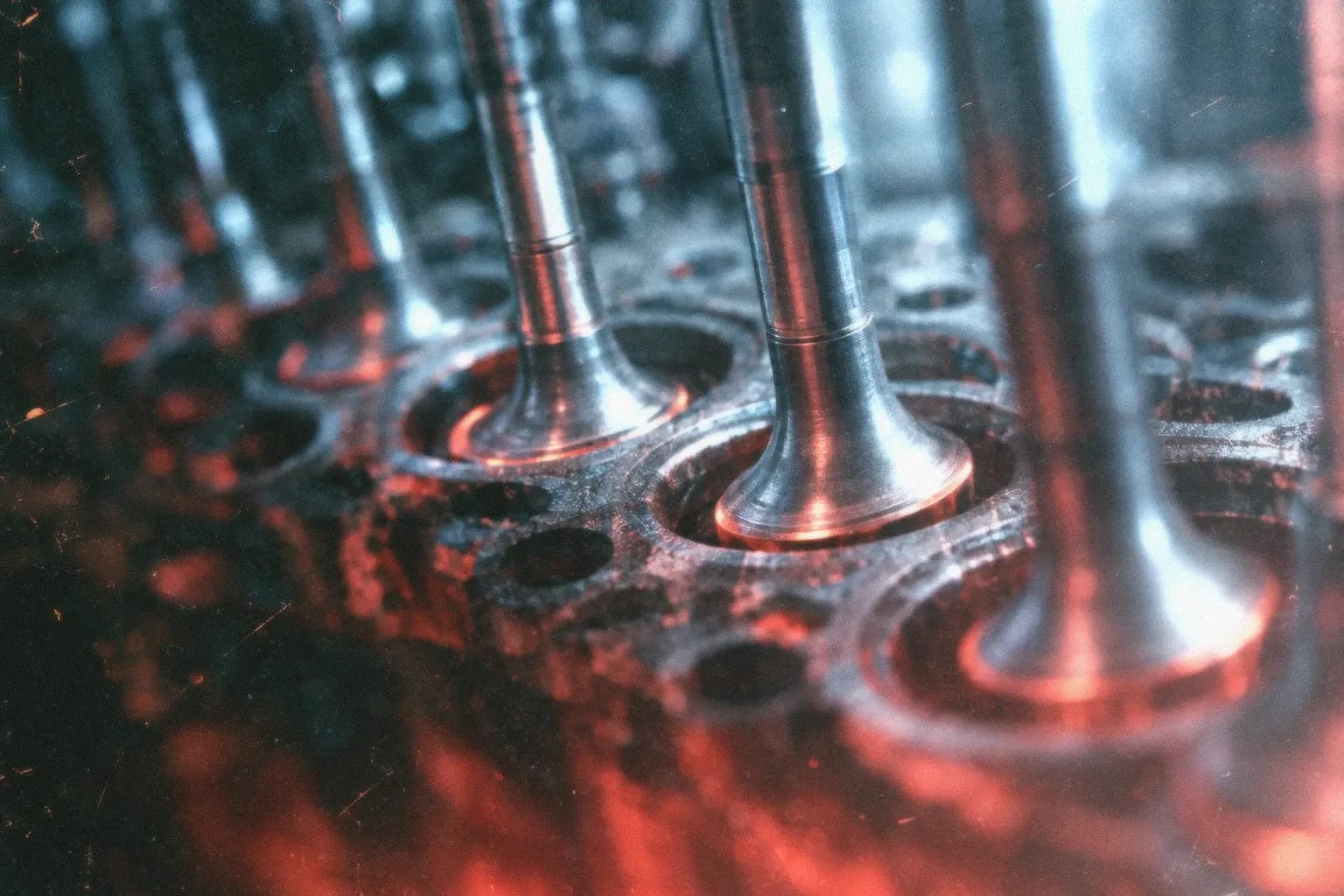 Steel valve stems descending into open ports, dramatically lit